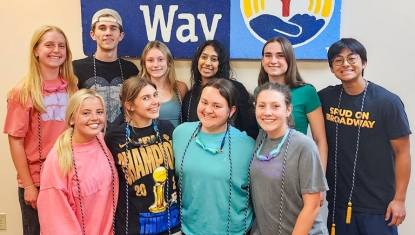 Students stand in front of a wall